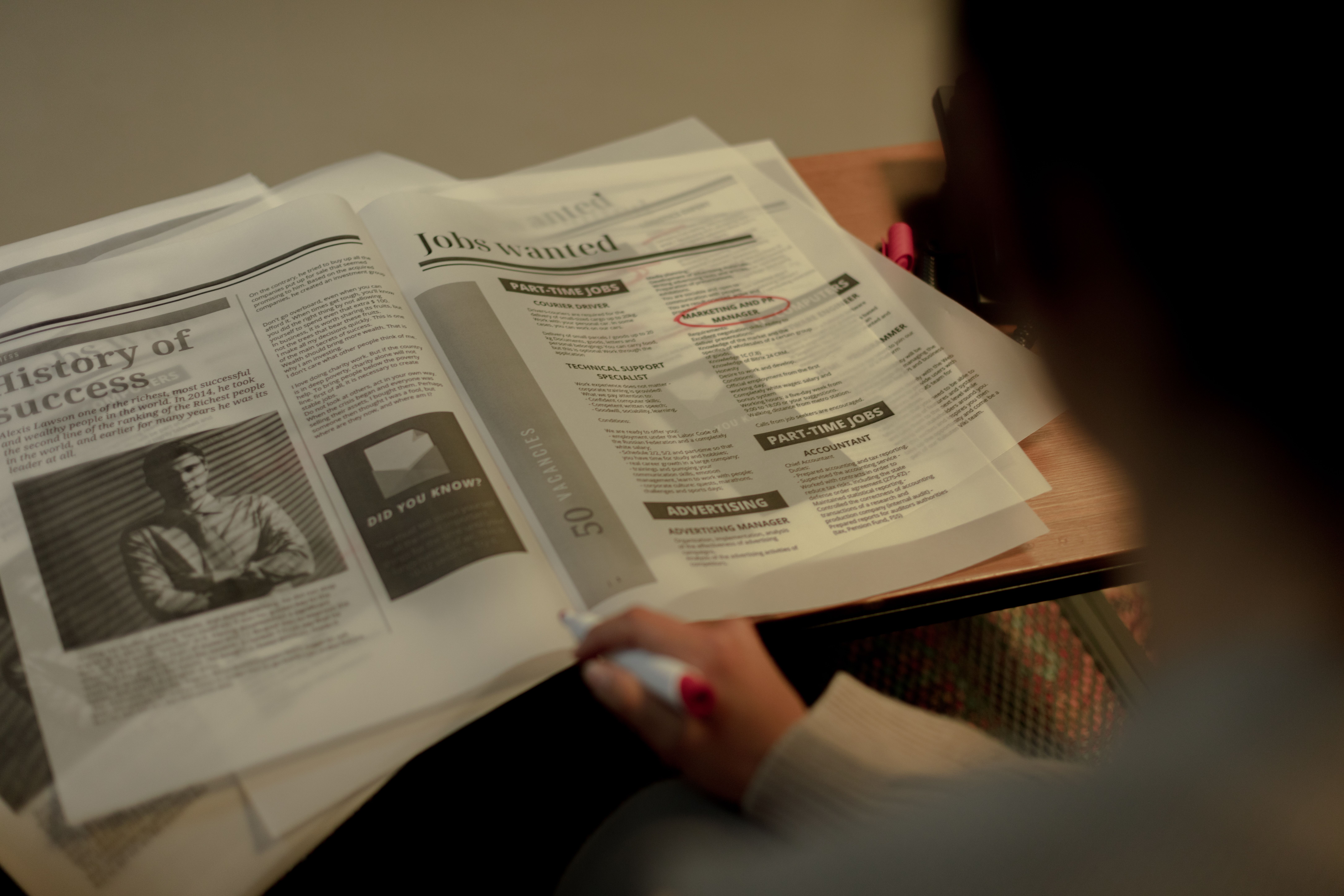 A job seeker reviewing newspaper job listings while preparing an application